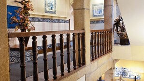 A grand staircase with ornate balustrades, a tiled floor, and a decorative vase. - Hotel Internacional (Porto)
