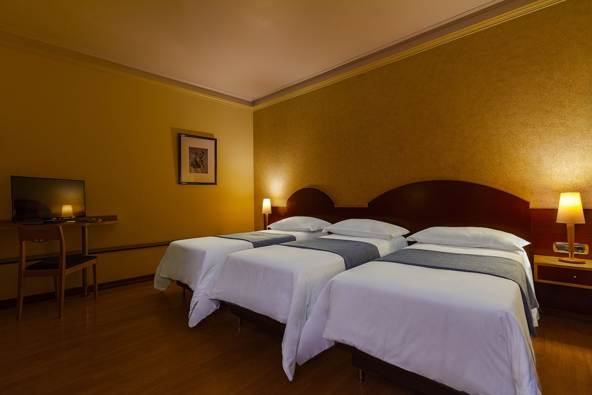 A hotel room with two beds, a desk, and a television.