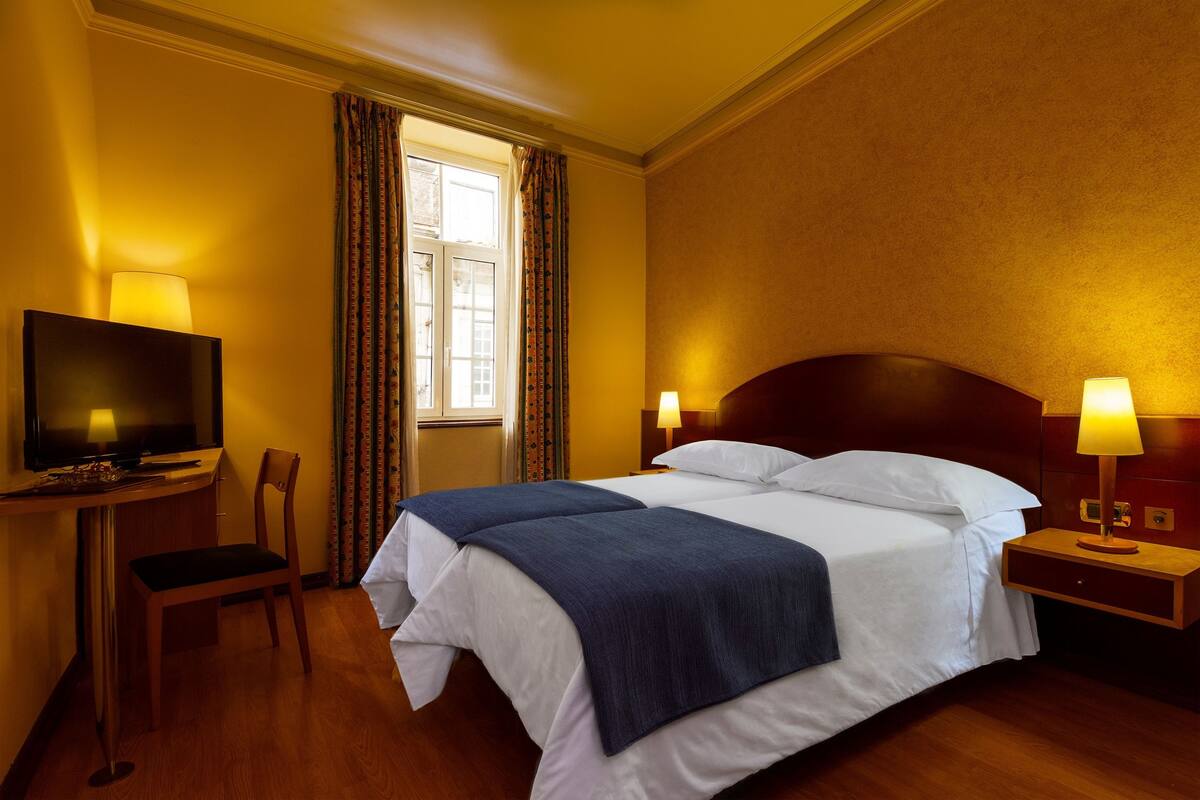 A hotel room with a bed, a television, a desk, and a chair.