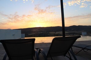 Una piscina al aire libre, sombrillas, sillones reclinables de piscina