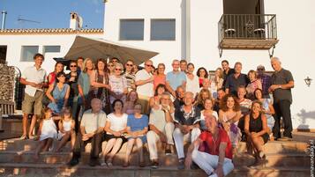 A group of people gathered on outdoor steps in front of a building with a balcony and a satellite dish.