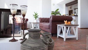 A living room with a brown leather sofa, a white table, and a decorative vase. - Arriadh Hotel (Ronda)