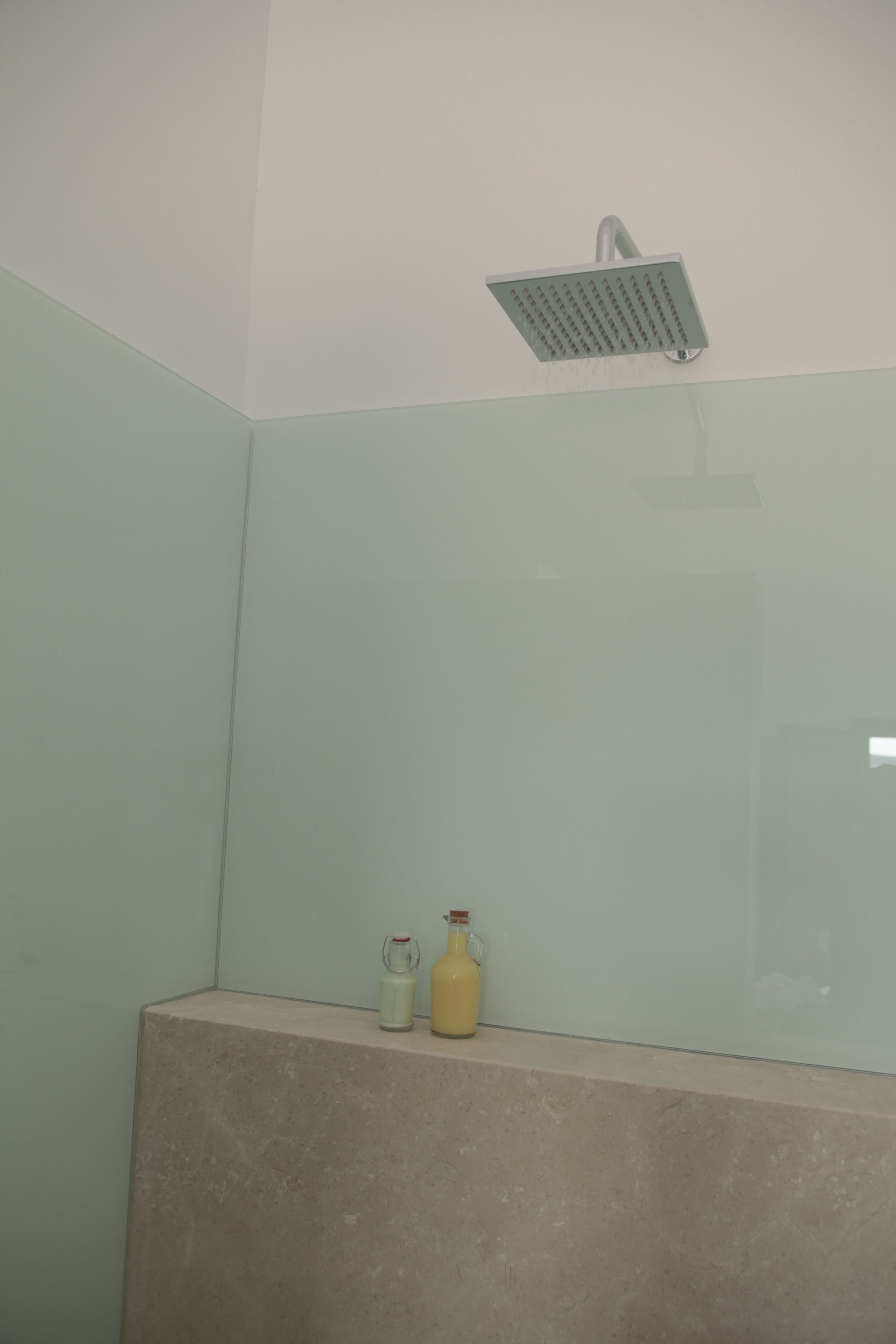 A bathroom with a shower, a sink, and a bottle of lotion on the counter.