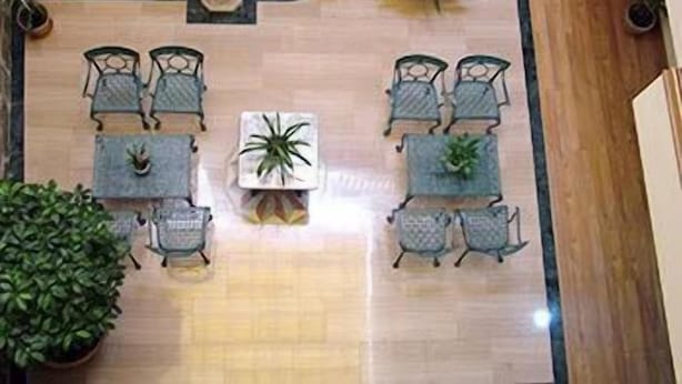 A spacious indoor seating area with a central table surrounded by chairs, potted plants, and a stone wall.