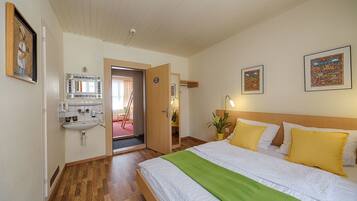 A bedroom with a bed, a bedside table, a mirror, and a wall-mounted sink.