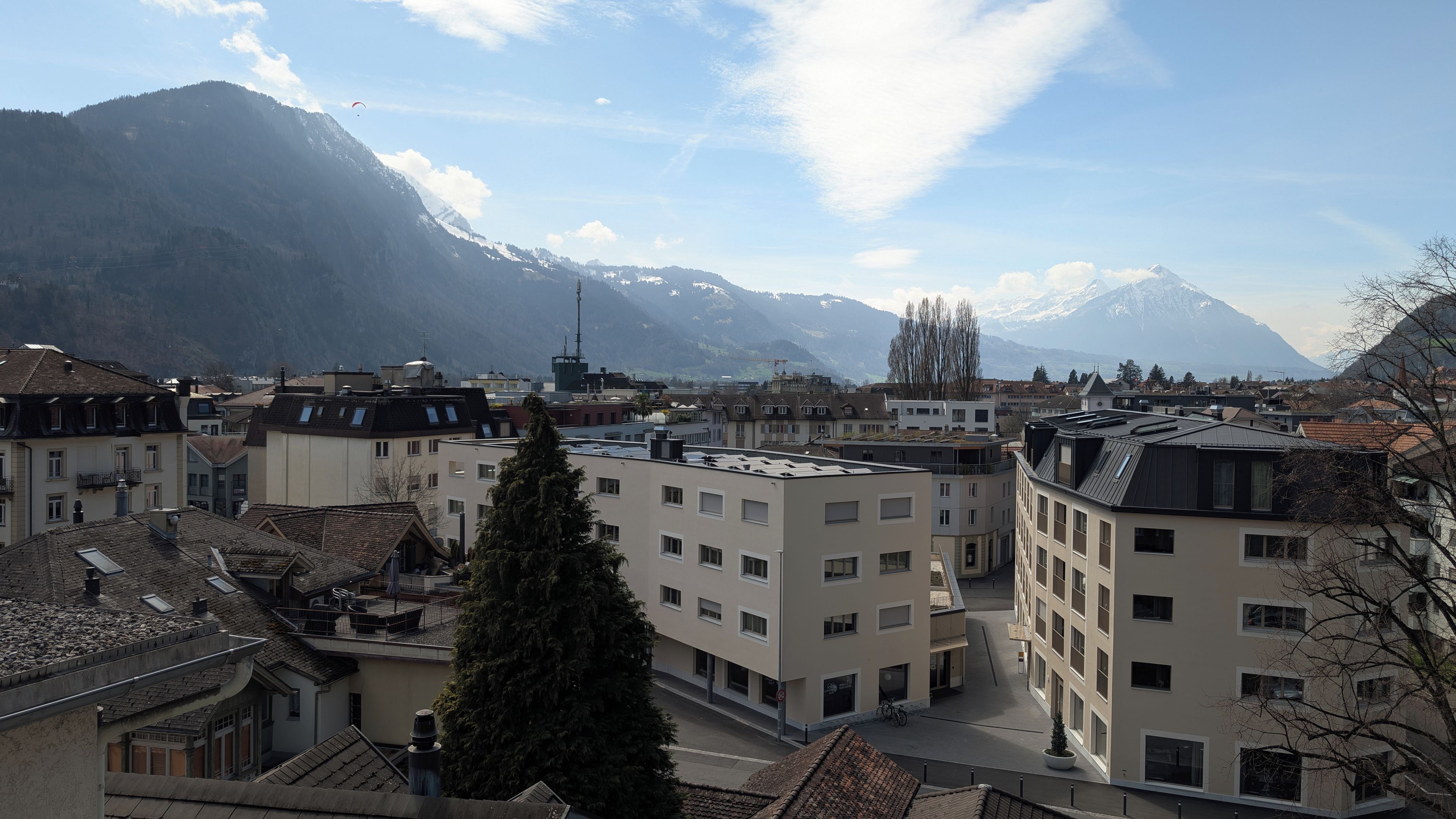 A view of a town with buildings and mountains in the background.