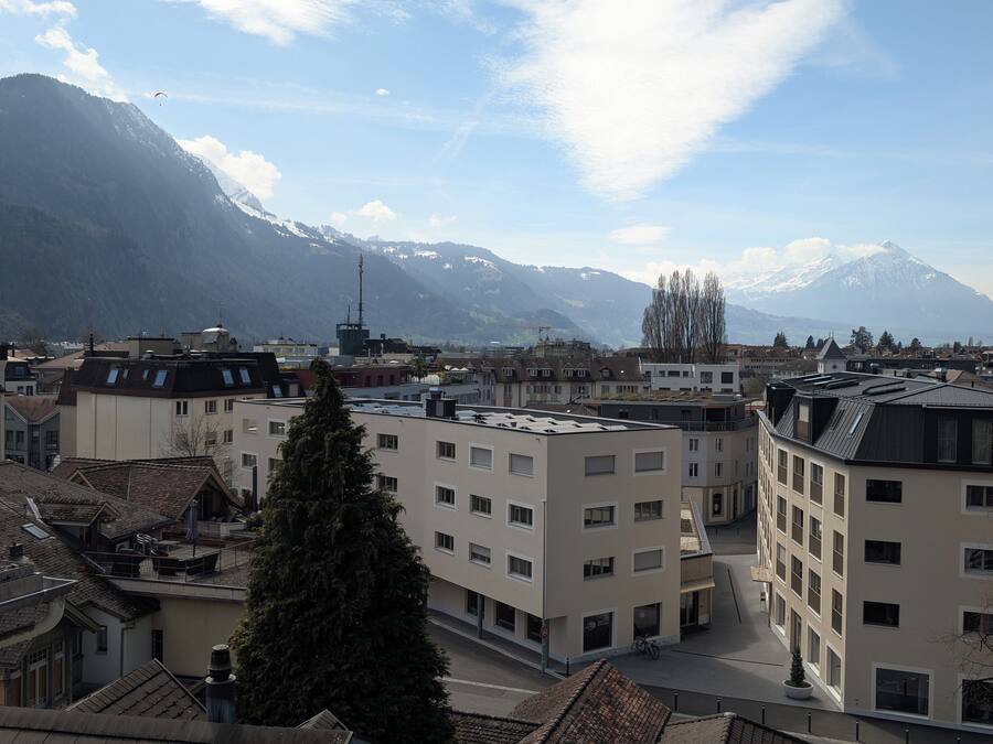 A view of a town with buildings and mountains in the background.