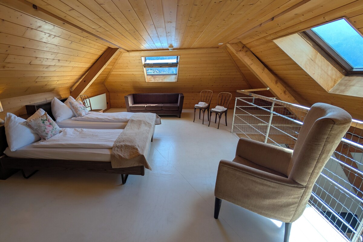 A cozy attic bedroom with two beds, a sofa, a chair, and a skylight.
