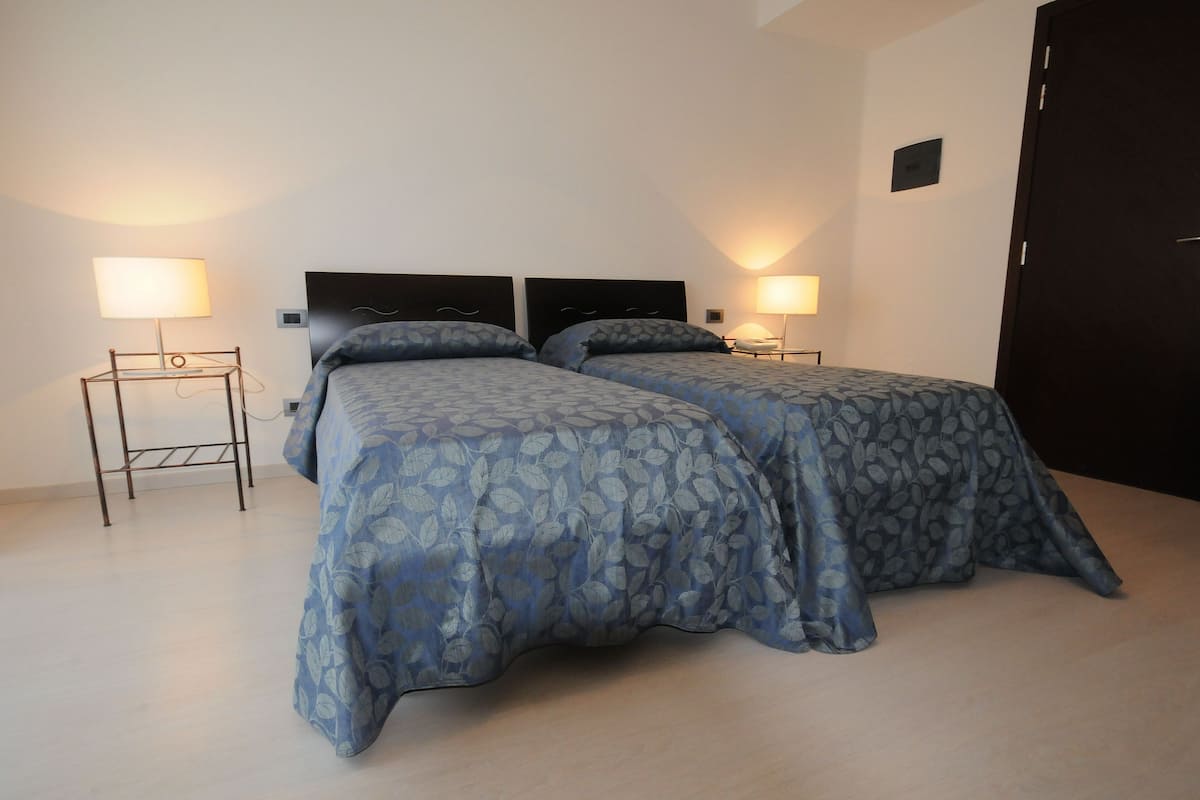 A double room with two beds, each with a headboard and bedside tables.