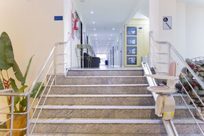 Un vestíbulo de hotel con una escalera que conduce a la recepción.