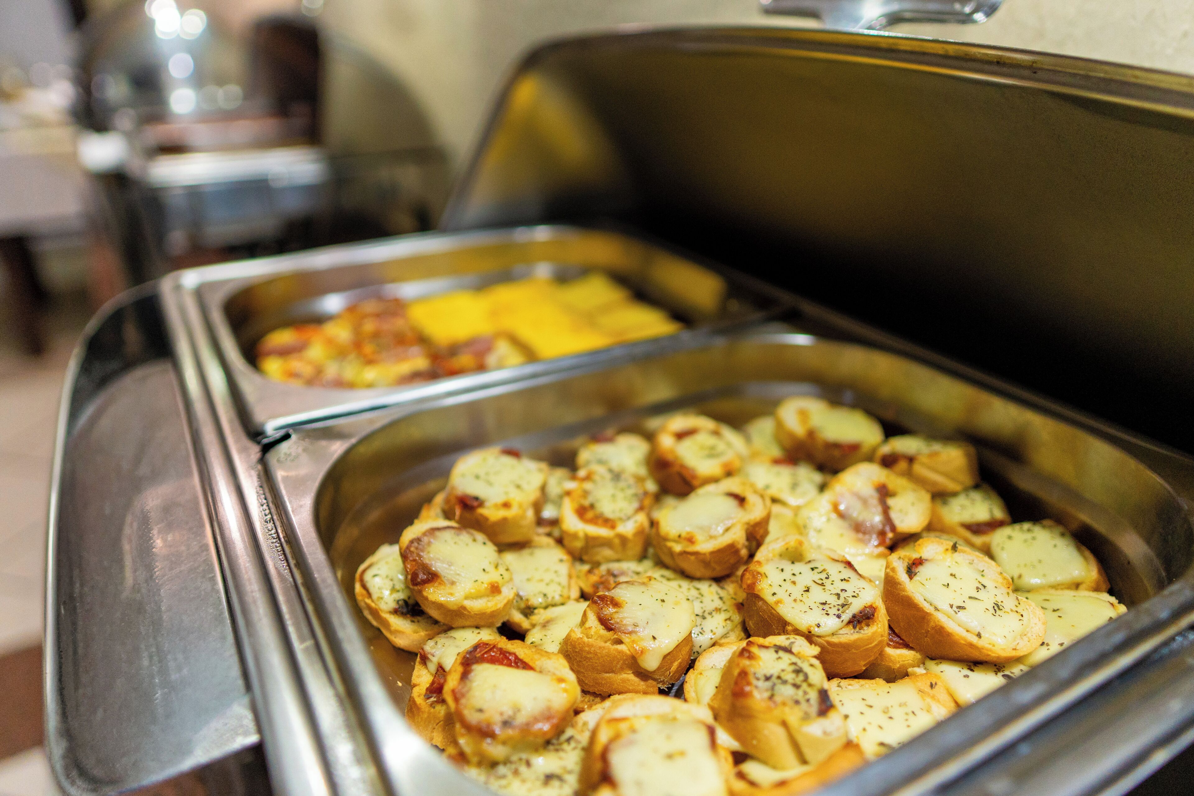 A buffet with sliced potatoes and cheese.