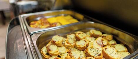 A buffet with sliced potatoes and cheese.