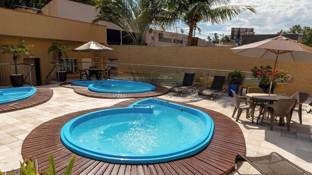 A rooftop pool area with multiple hot tubs, lounge chairs, and tables.