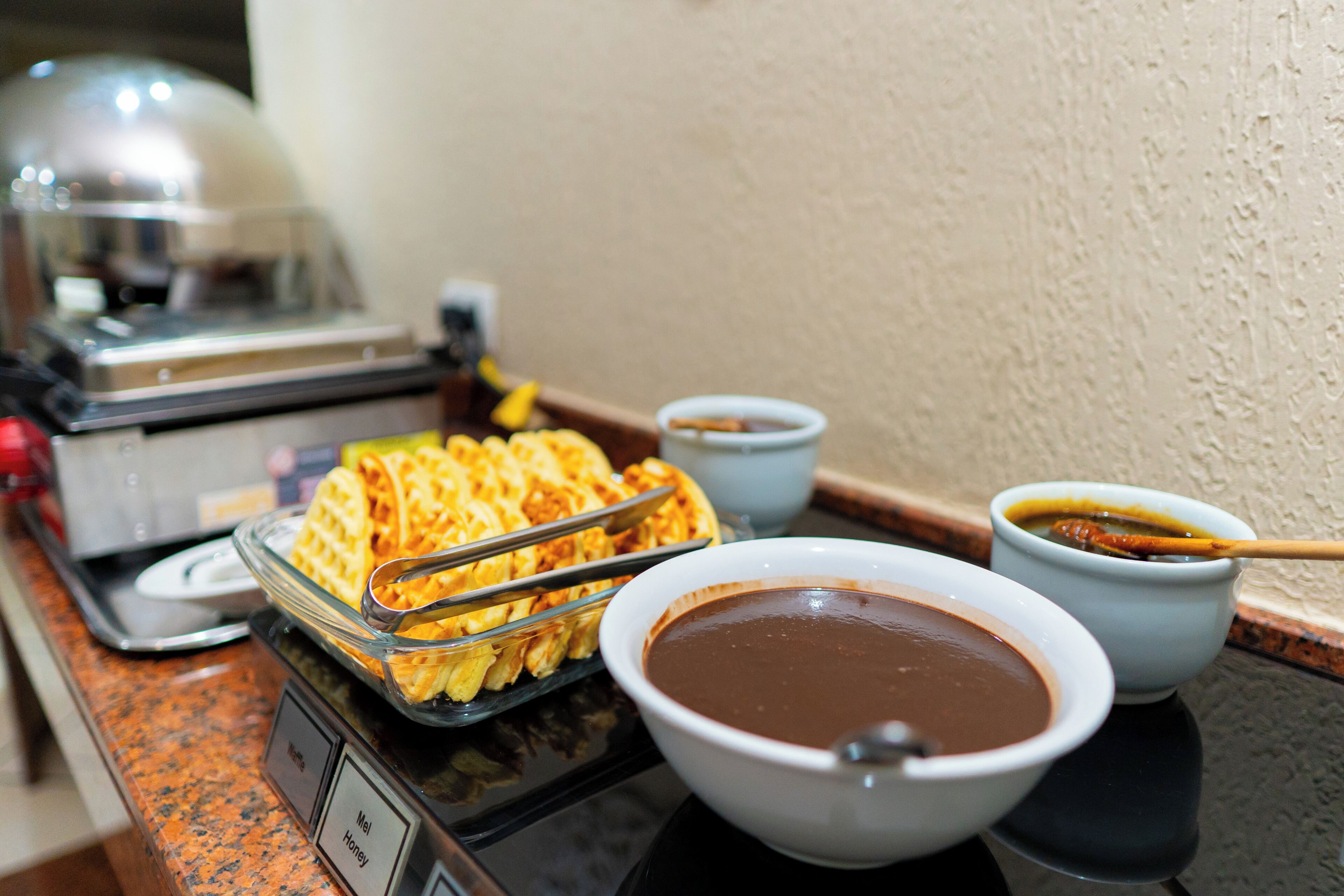 Montaje de bufé con waffles, tazones de sopa y una plancha para waffles.