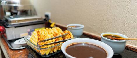 Montaje de bufé con waffles, tazones de sopa y una plancha para waffles.