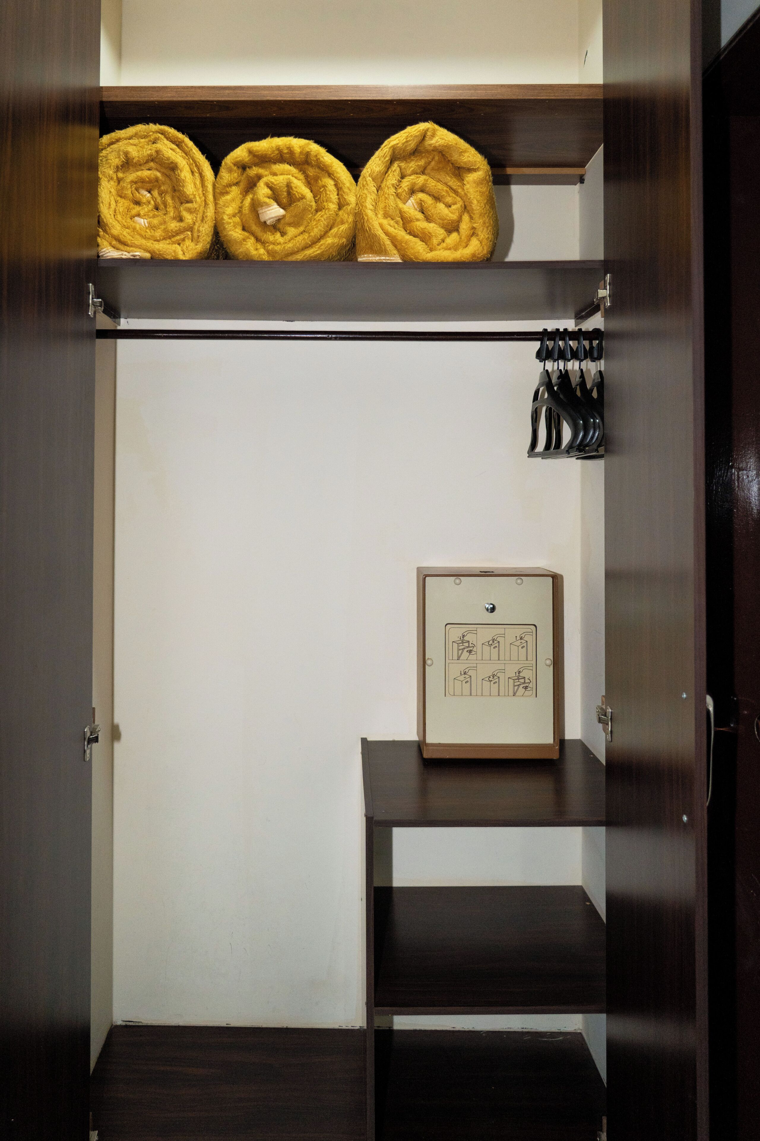 A wardrobe with three yellow towels, a framed picture, and a coat rack with hanging items.