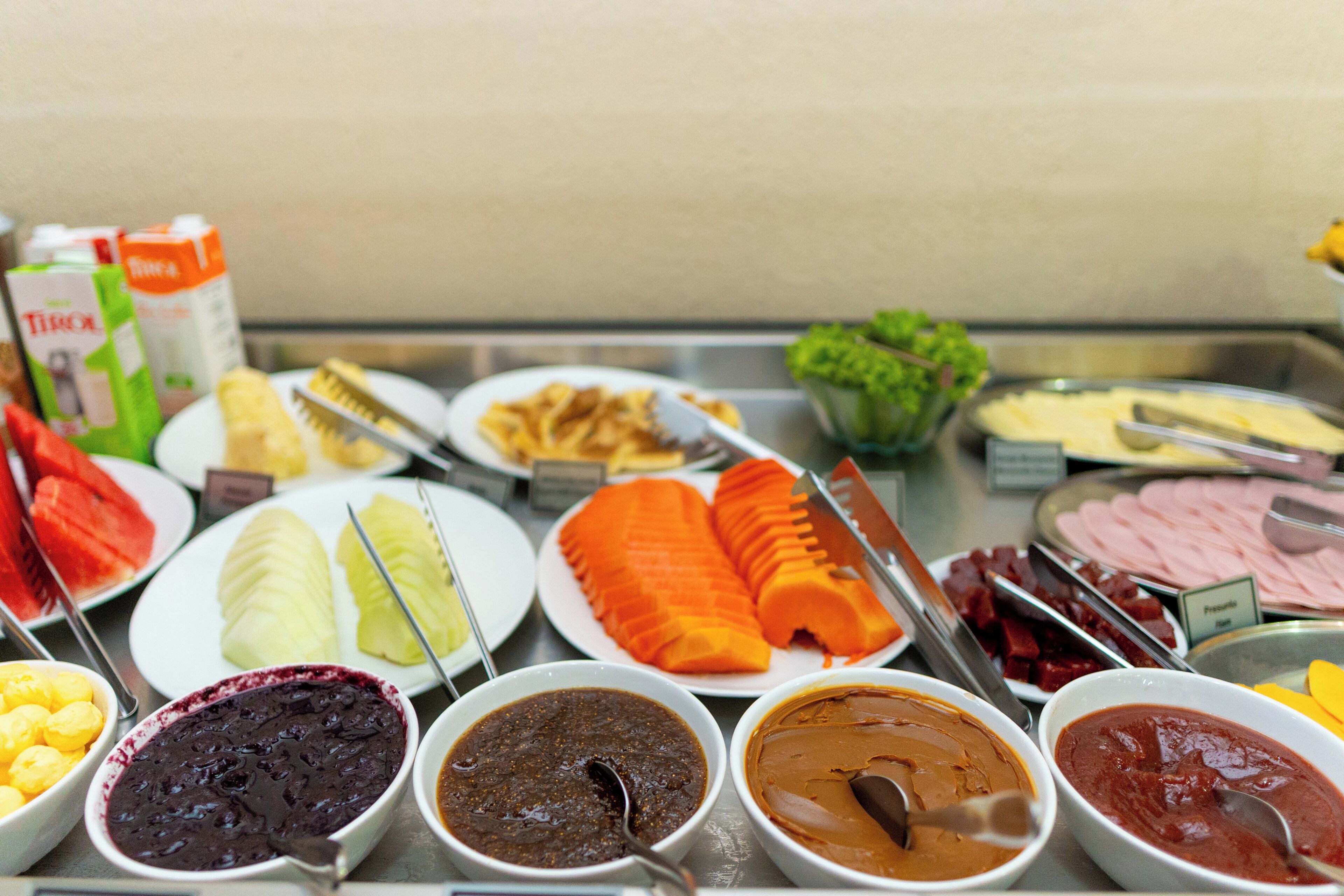 A buffet with various food items including fruits, vegetables, and different sauces.