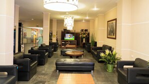 A lobby with leather sofas, a wooden coffee table, a TV, and a large decorative light fixture.