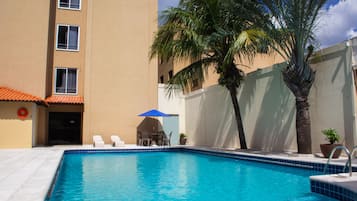 Una piscina al aire libre, sillones reclinables de piscina
