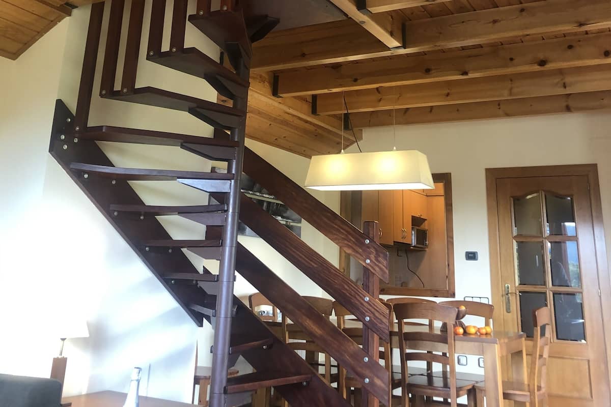 A wooden staircase with a metal handrail leading to a loft area.
