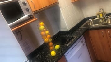 Una cocina equipada con microondas, lavavajillas y fregadero.
