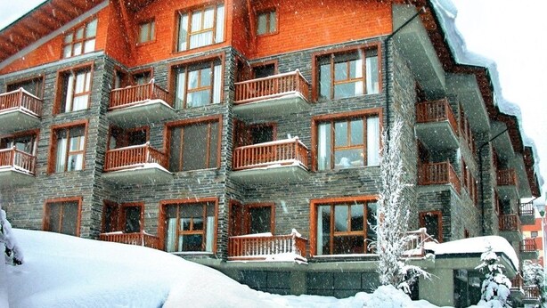 Un hotel de diverses plantes amb balcons, finestres grans i façana de pedra.