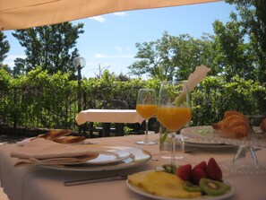 An outdoor dining setup with a table, plates, cutlery, and a croissant. - Villa Lauri (Neive)