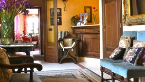 A traditional living room with a sofa, armchairs, a coffee table, and a fireplace. - Villa Lauri (Neive)