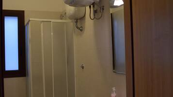 Une salle de bain avec douche, toilettes et lavabo.