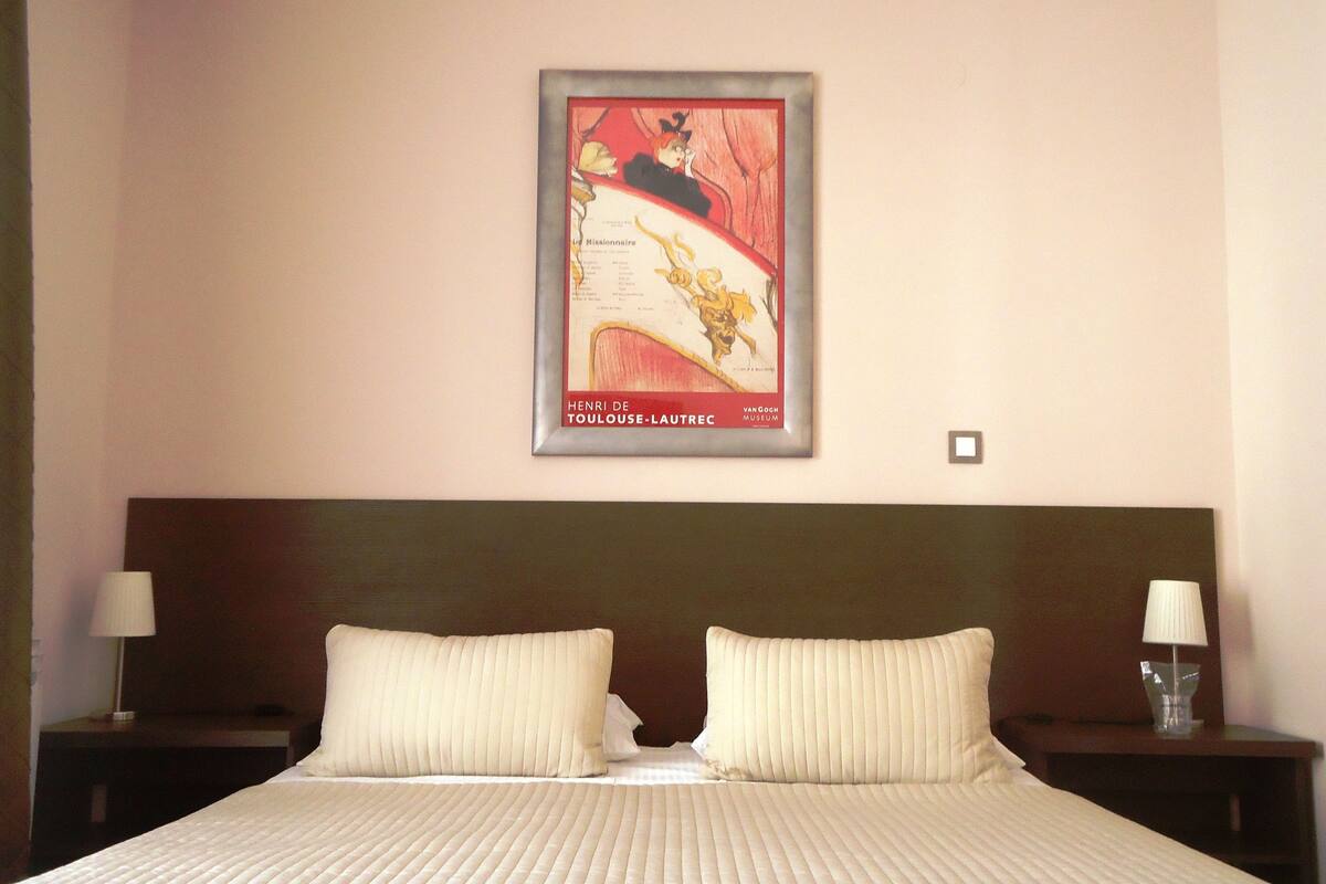 A hotel room with a large bed, two nightstands, and a framed picture on the wall.