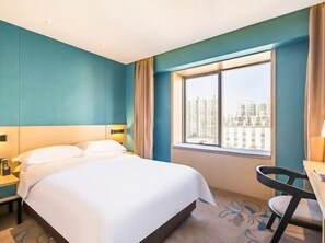 Una habitación de hotel con una cama grande, un escritorio y una ventana con vistas a la ciudad.