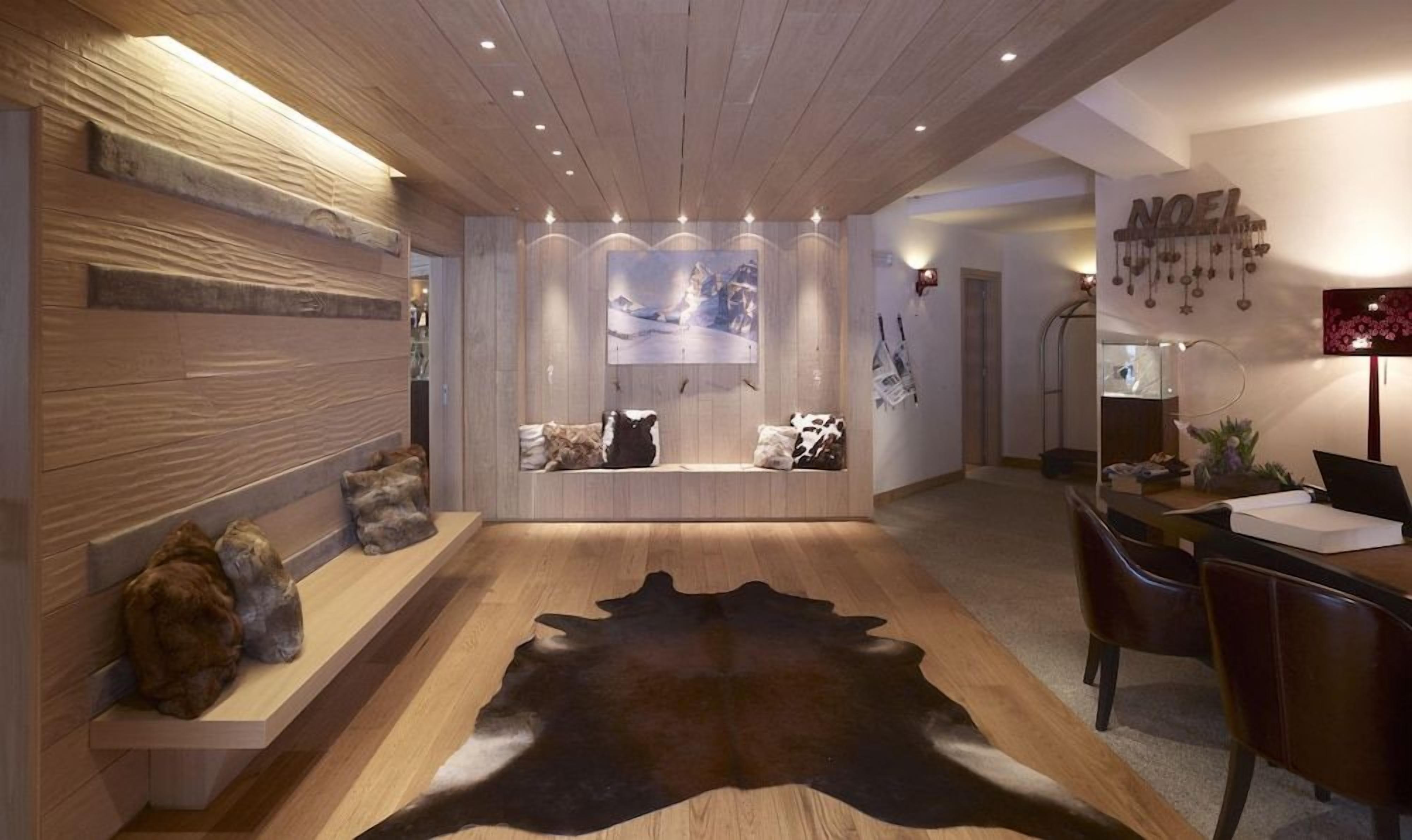 A modern interior with a wooden ceiling, a central seating area with a large rug, and a wall-mounted artwork.