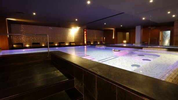 Un área de spa con un jacuzzi grande, zona de estar y un mostrador de recepción.