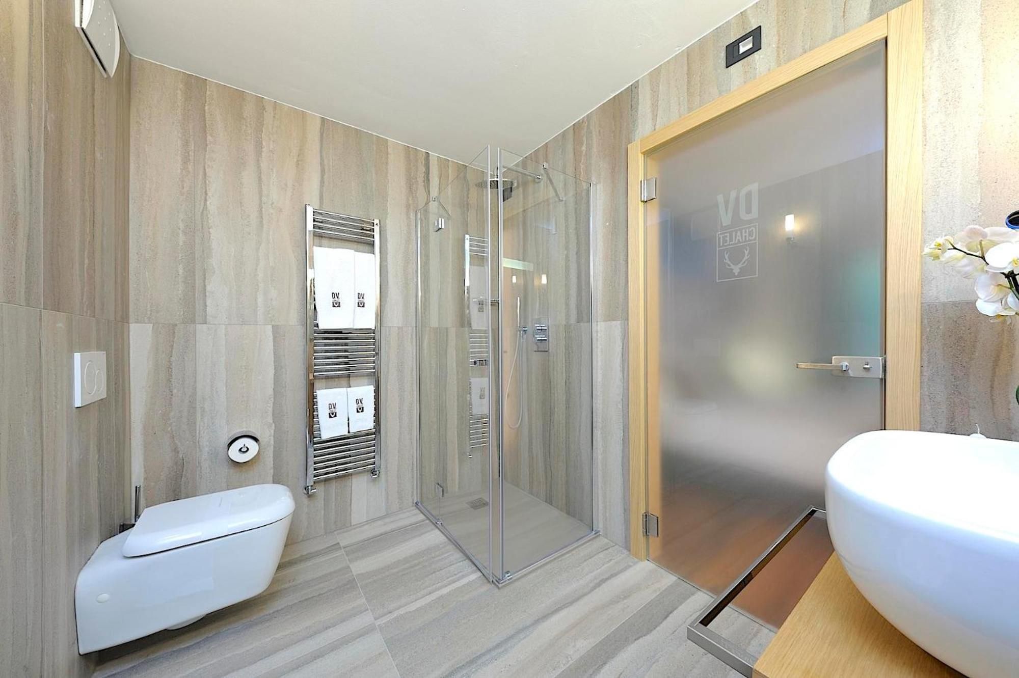 A modern bathroom with a toilet, shower, and sink.