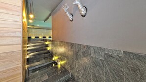 Una escalera con paredes de mármol y paneles de madera que conduce a una habitación con una lámpara de techo.