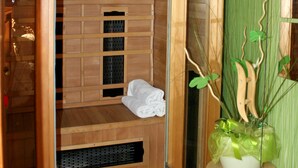 A sauna with a wooden interior, a towel rack, and a small table with a plant. - Hotel Casanova (Duchcov)