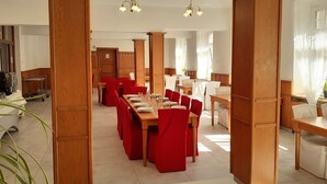 A spacious dining area with multiple tables and chairs, wooden paneling, and pendant lighting. - Hotel Casanova (Duchcov)