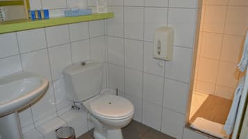 A bathroom with a toilet, sink, and a soap dispenser on the wall.