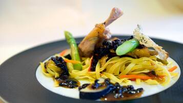 Un plato de comida con fideos, verduras y un trozo de carne.