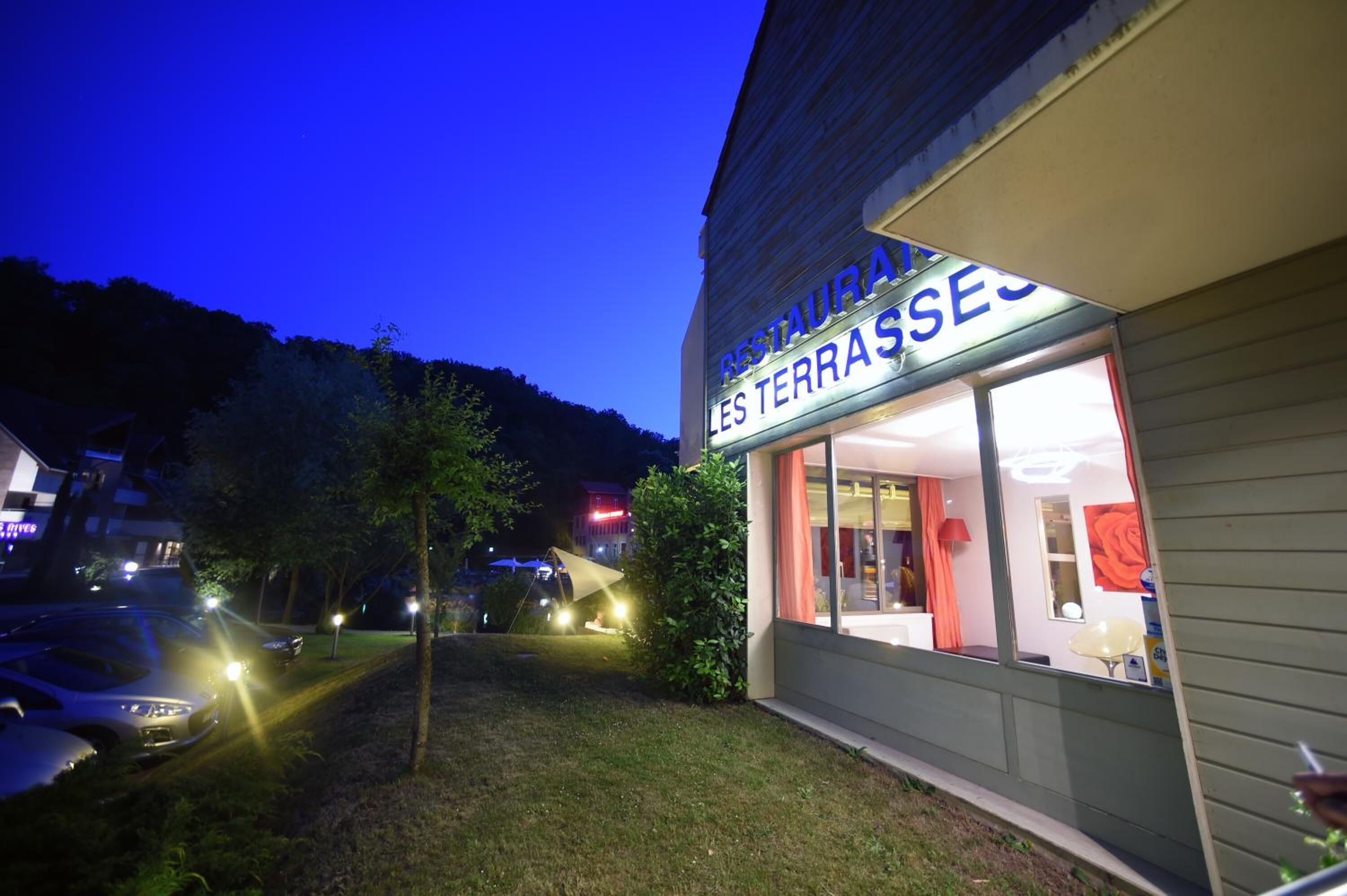 Un restaurante con un letrero que dice "RESTAURANT LES TERRASSES" al atardecer.