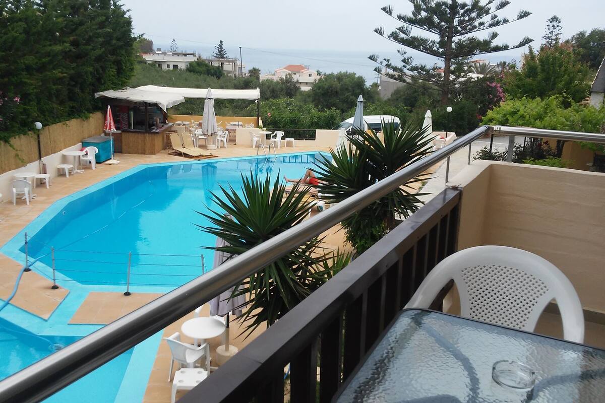 A swimming pool with a view of the sea, surrounded by lounge chairs and umbrellas.