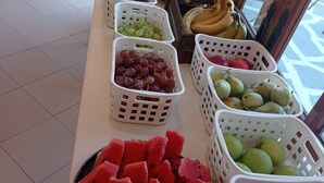 A fruit display with various fruits in baskets and a plate of watermelon slices. - Alexandros Studios (Chania)