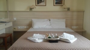 A hotel room with a bed, a desk, and a chair. There are two paintings on the wall above the bed. - Alexandros Studios (Chania)