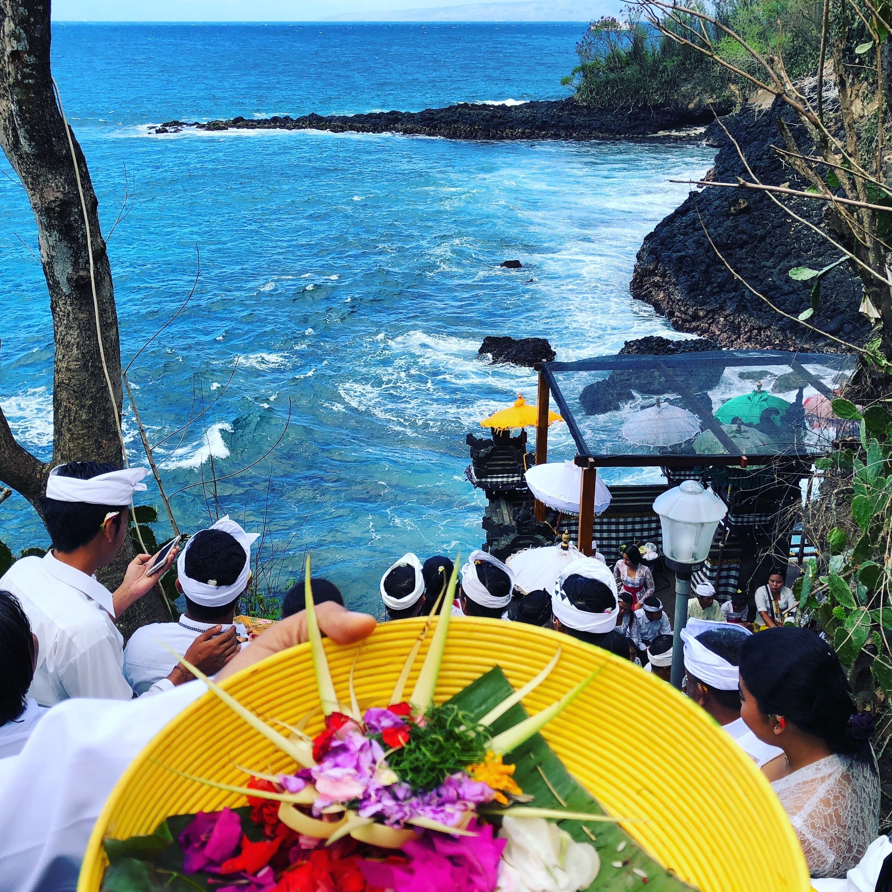 A coastal view with a rocky shoreline and a gathering of people.
