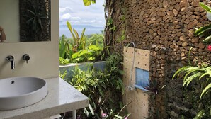 Un baño con pared de piedra, un lavamanos y una ducha.