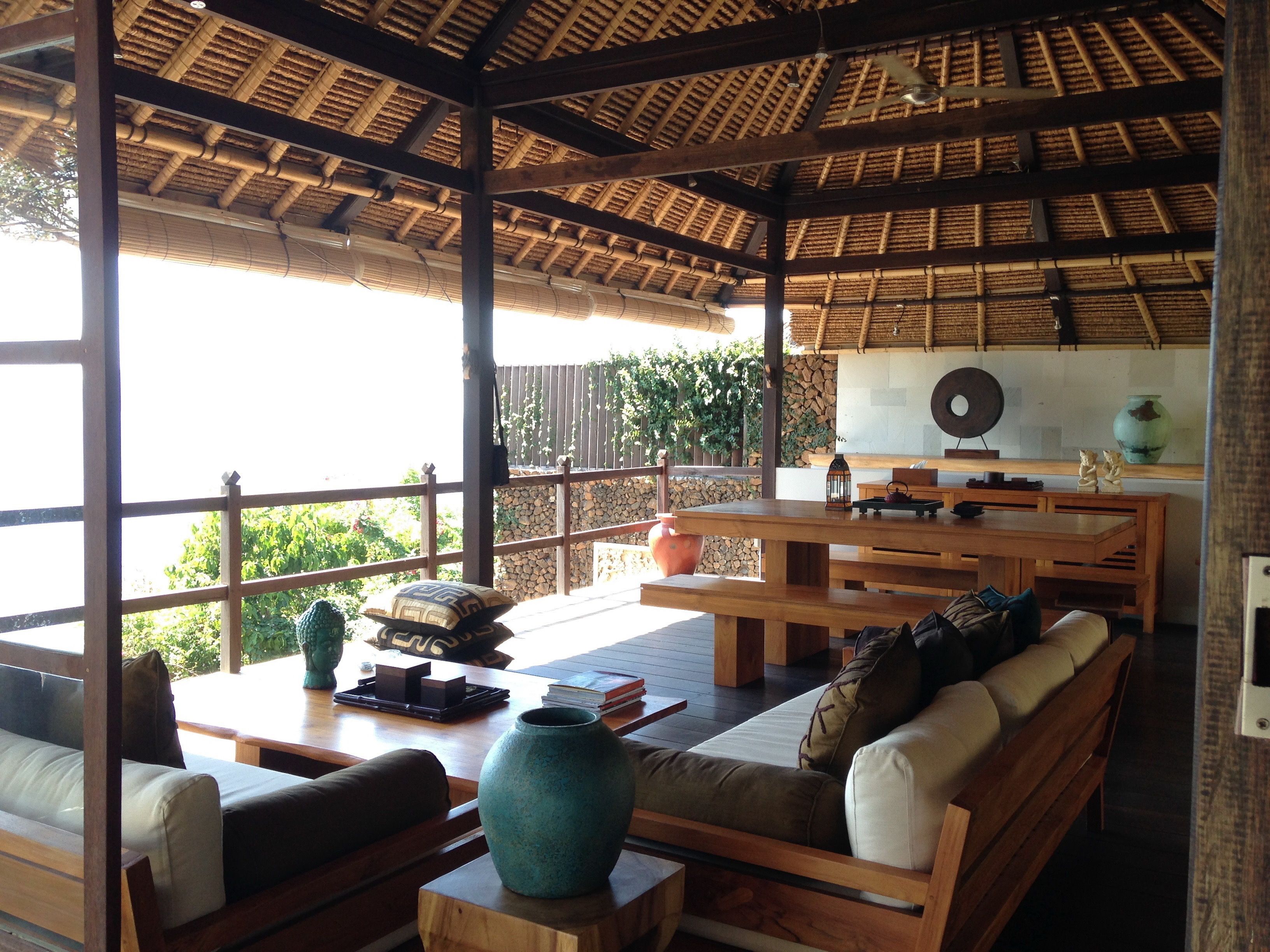 Un espacio de estar al aire libre techado con muebles de madera y techo de paja.