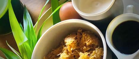 A table with a bowl of shredded food, a cup of coffee, a plate with eggs, and a pitcher of a white liquid.