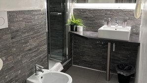 Ein modernes Badezimmer mit einem Bidet, einem Waschbecken und einer Duschkabine aus Glas.