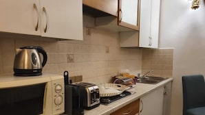 Eine kleine Küche mit Mikrowelle, Toaster, Wasserkocher und Spüle.