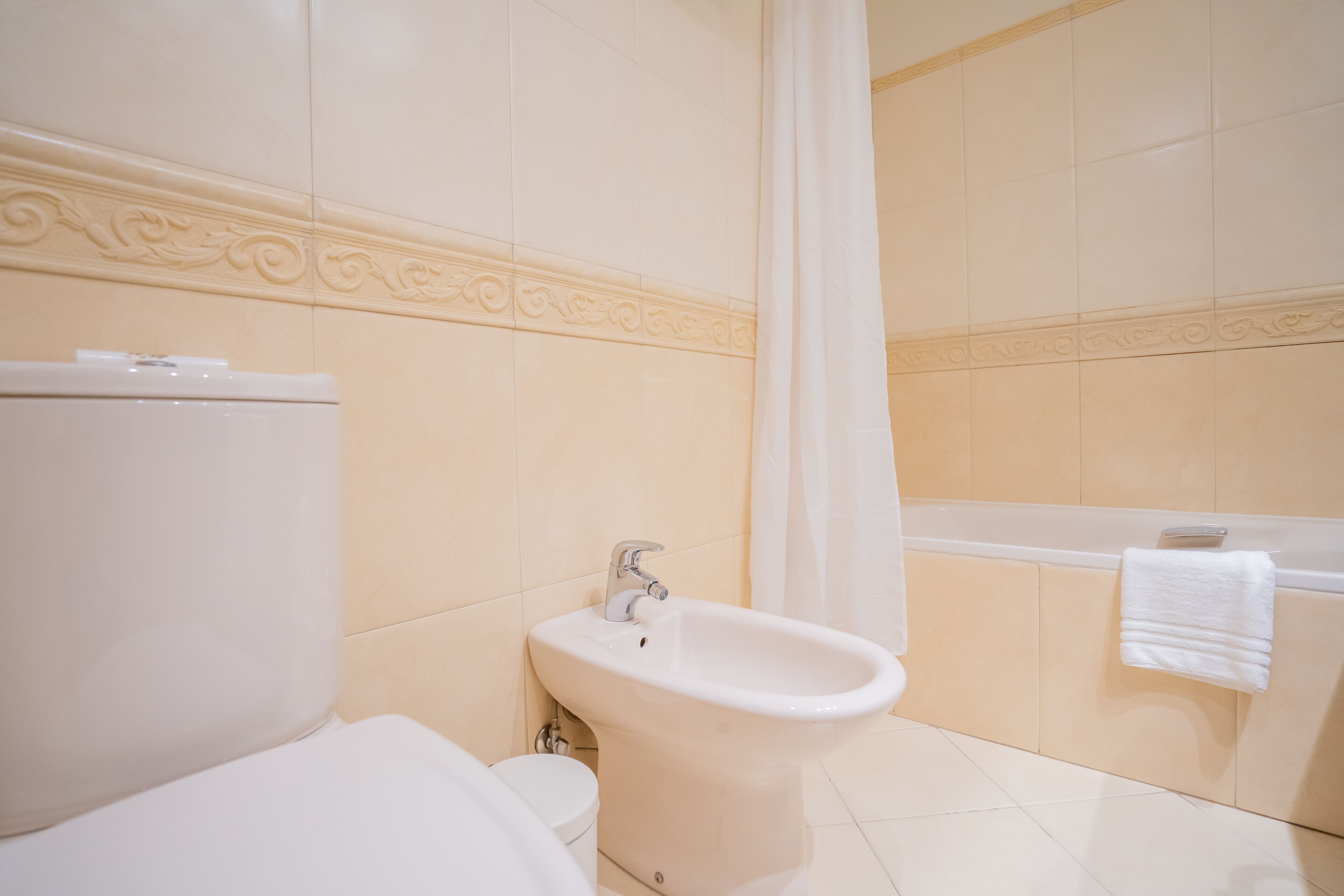 A bathroom with a toilet, bidet, and bathtub.